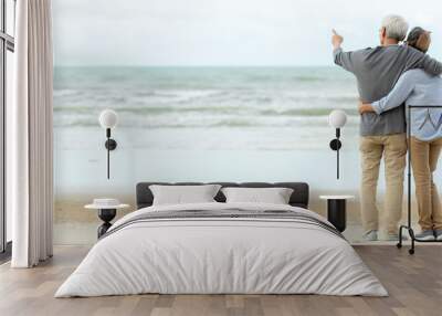 Asian Lifestyle senior couple hug and pointing on the beach happy in love romantic and relax time.   Wall mural